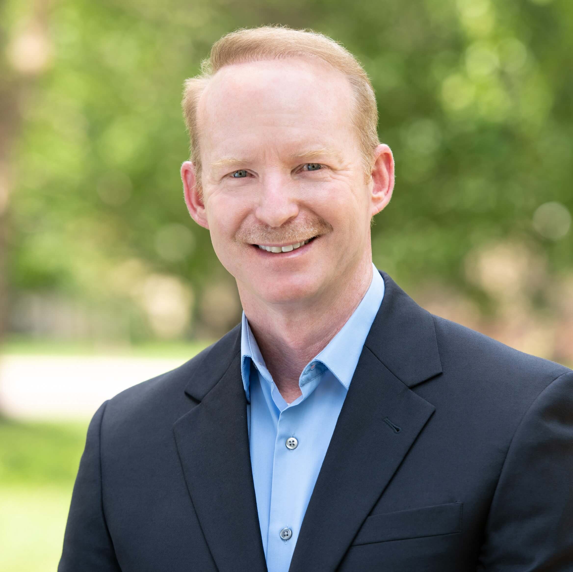 A man in a suit and tie smiling for the camera.